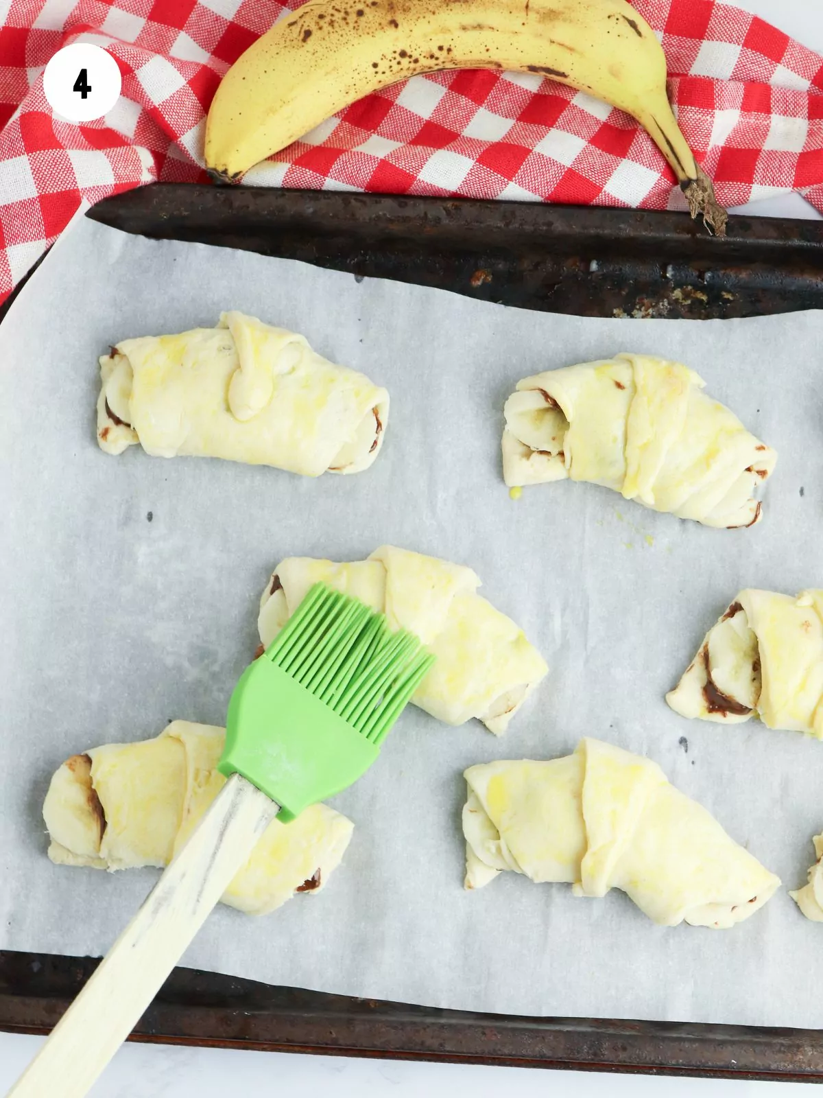 pastry brush adding egg wash to the crescent rolls