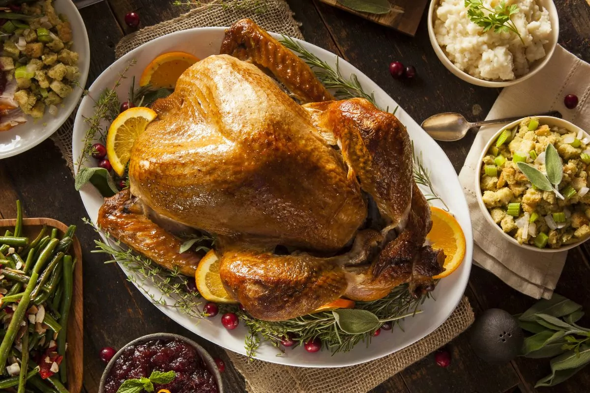 roast turkey on platter with Thanksgiving side dishes nearby.