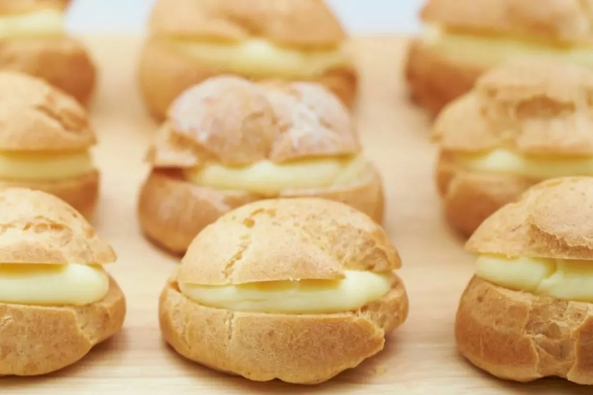 vanilla pudding filled cream puffs on wooden board. MSN.