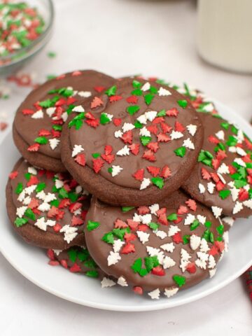 a plate of chocolate cookies with Christmas tree sprinkles.