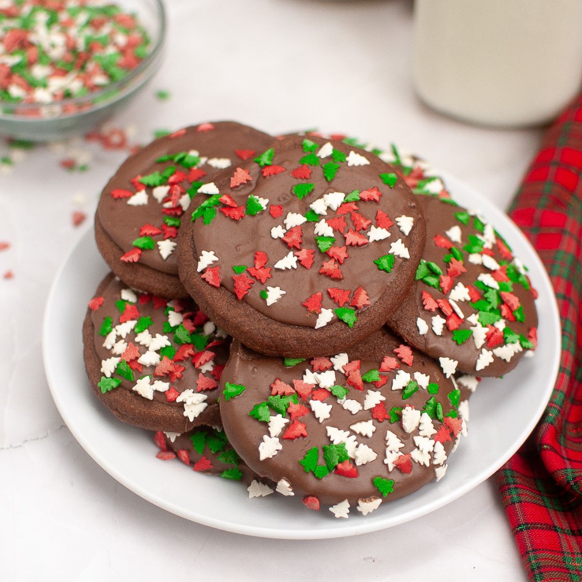 a plate of chocolate cookies with Christmas tree sprinkles.