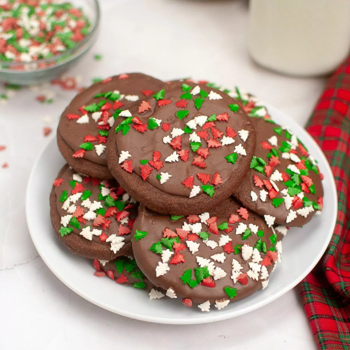 a plate of chocolate cookies with Christmas tree sprinkles.