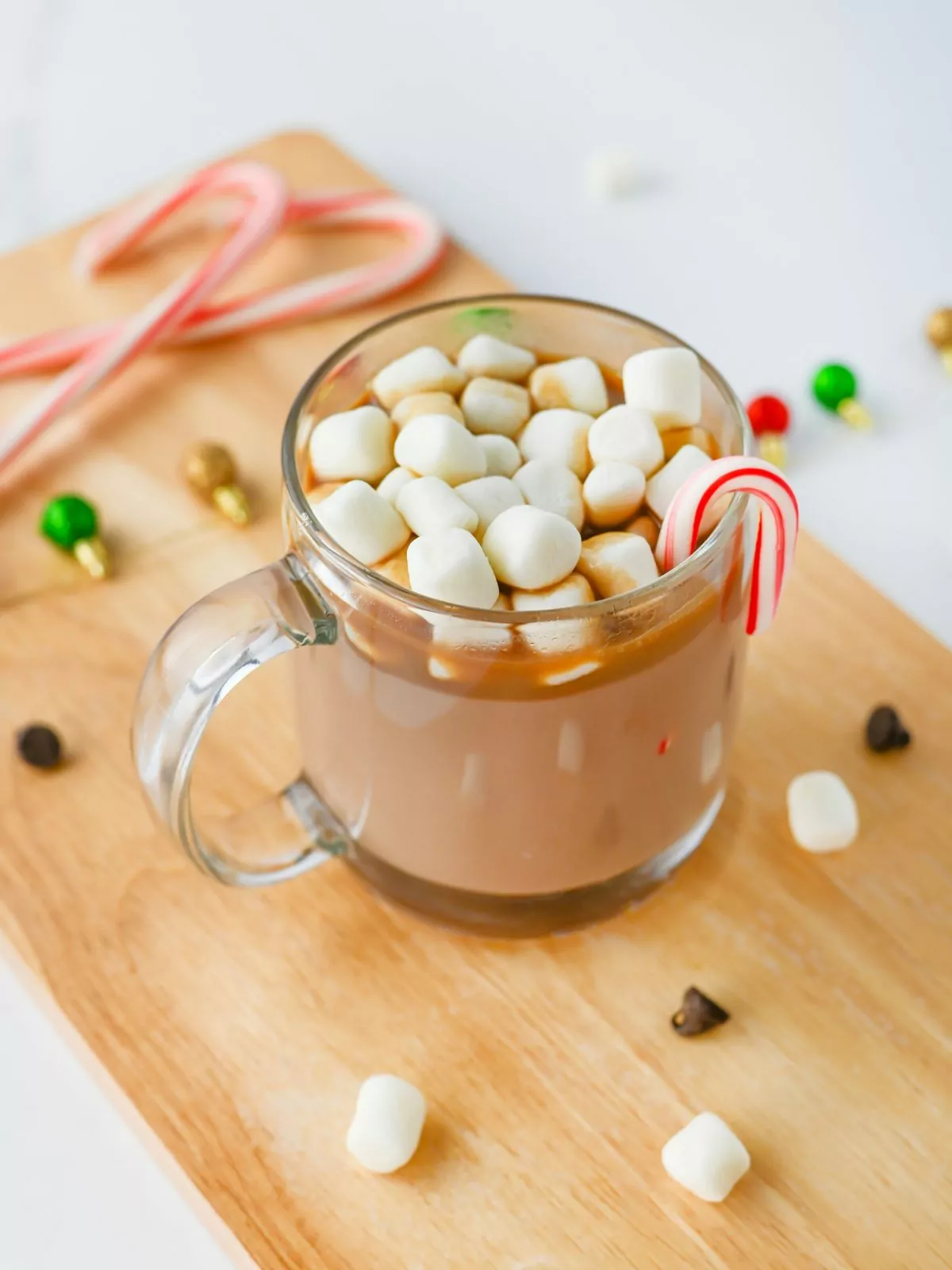 glass mug with hot chocolate with marshmallows, candy canes, chocolate chips.