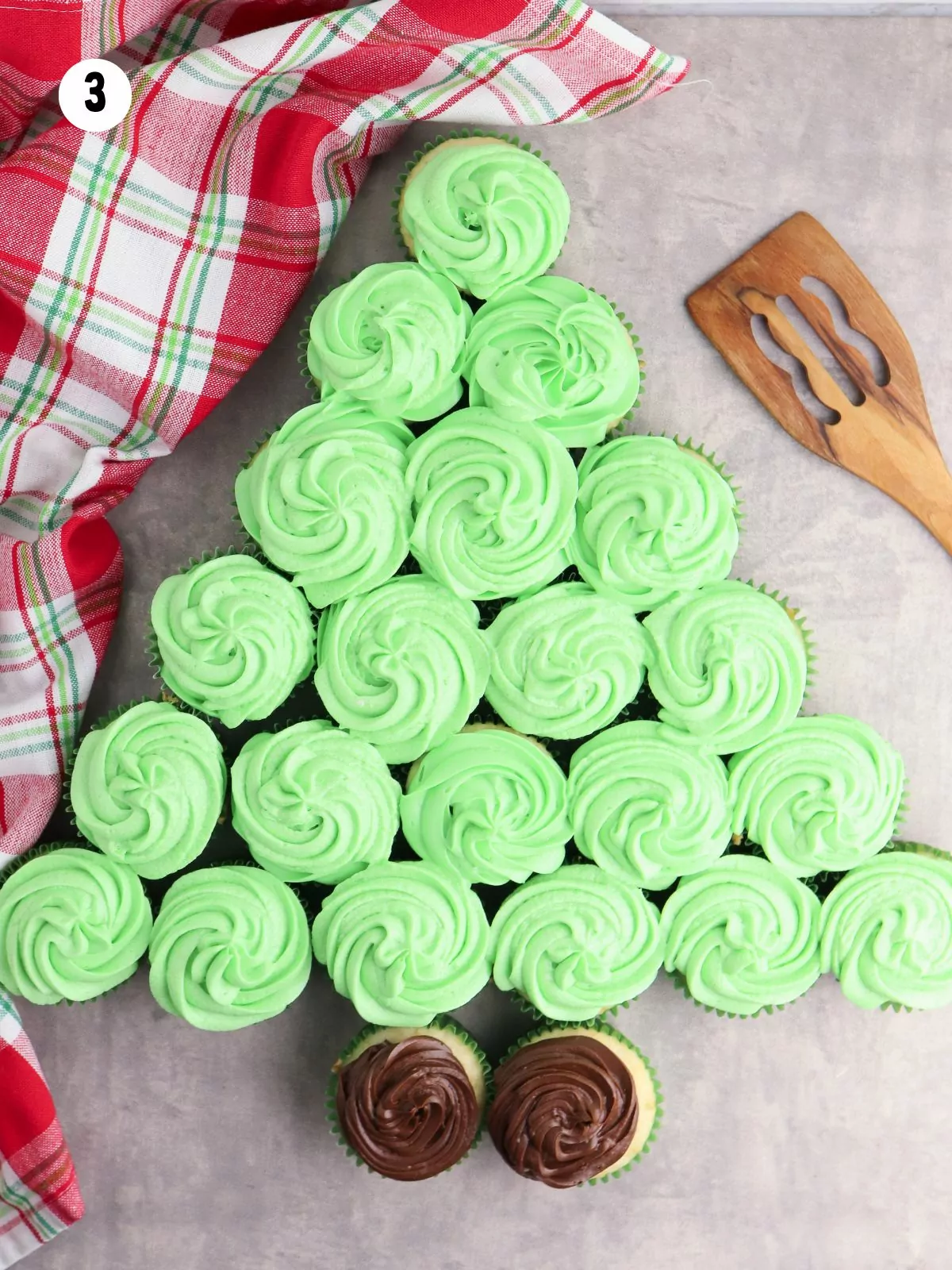 green frosted cupcakes in the shape of a tree with 2 chocolate frosted for the base.