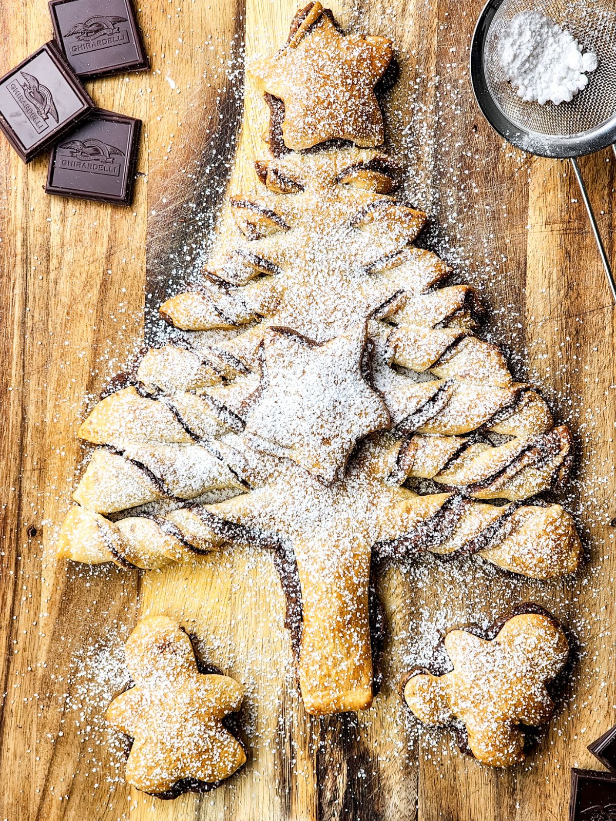 baked Christmas tree with hazelnut spread on cutting board with powdered sugar.