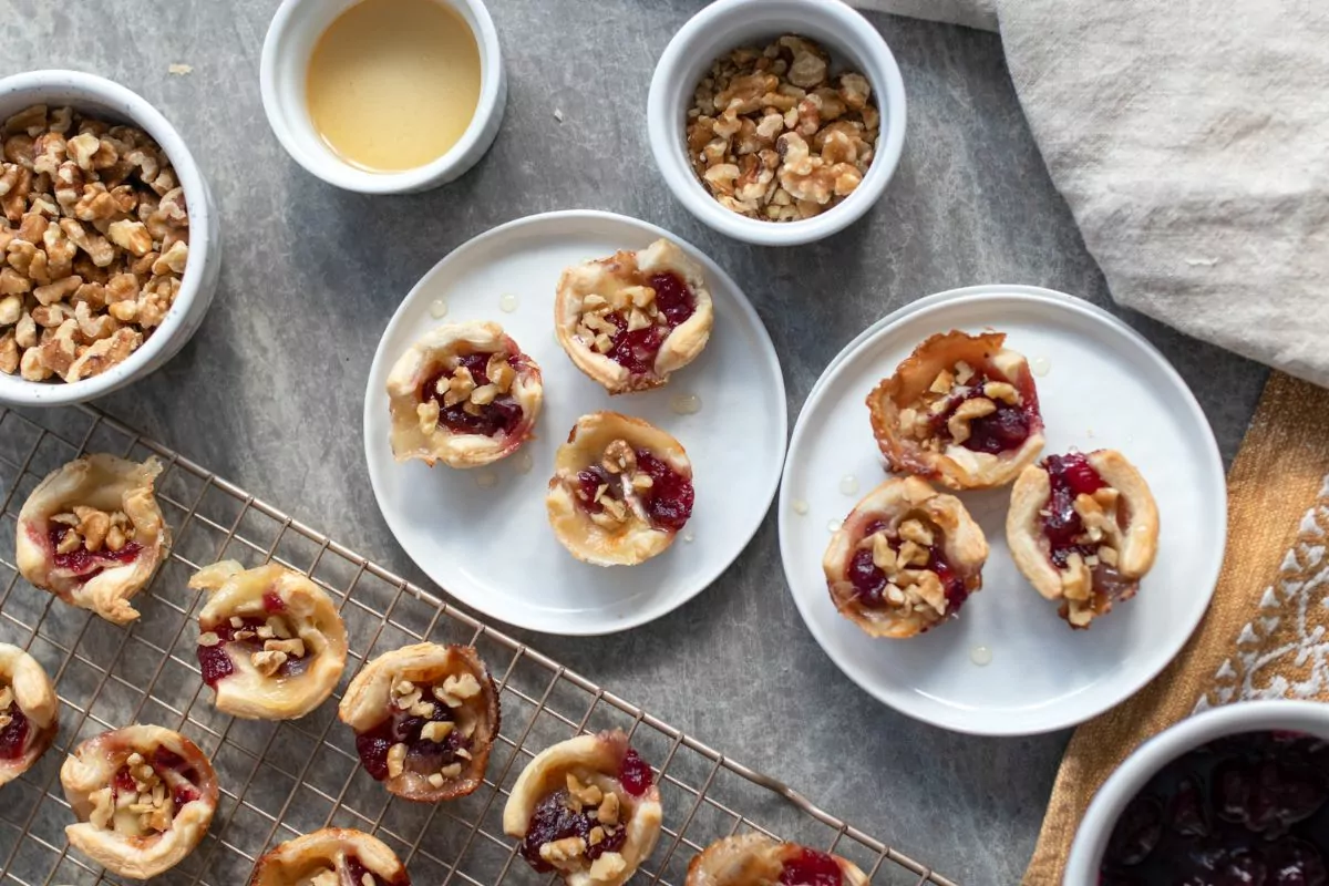 appetizer made with puff pastry, cranberries, cheese and nuts on plates and cooling rack.