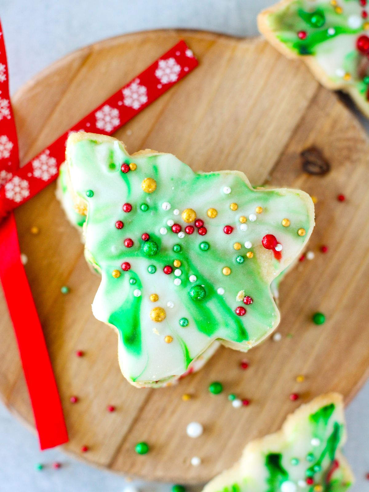 Christmas Tree Cookies with green marbled icing on a round wood board