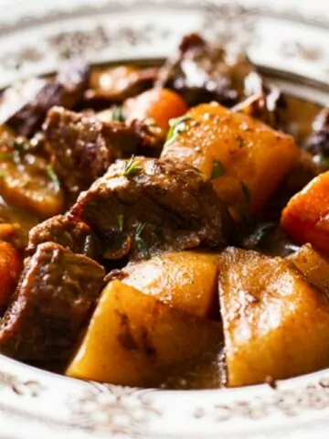 Irish beef stew with potatoes and carrots in bowl with spoon.