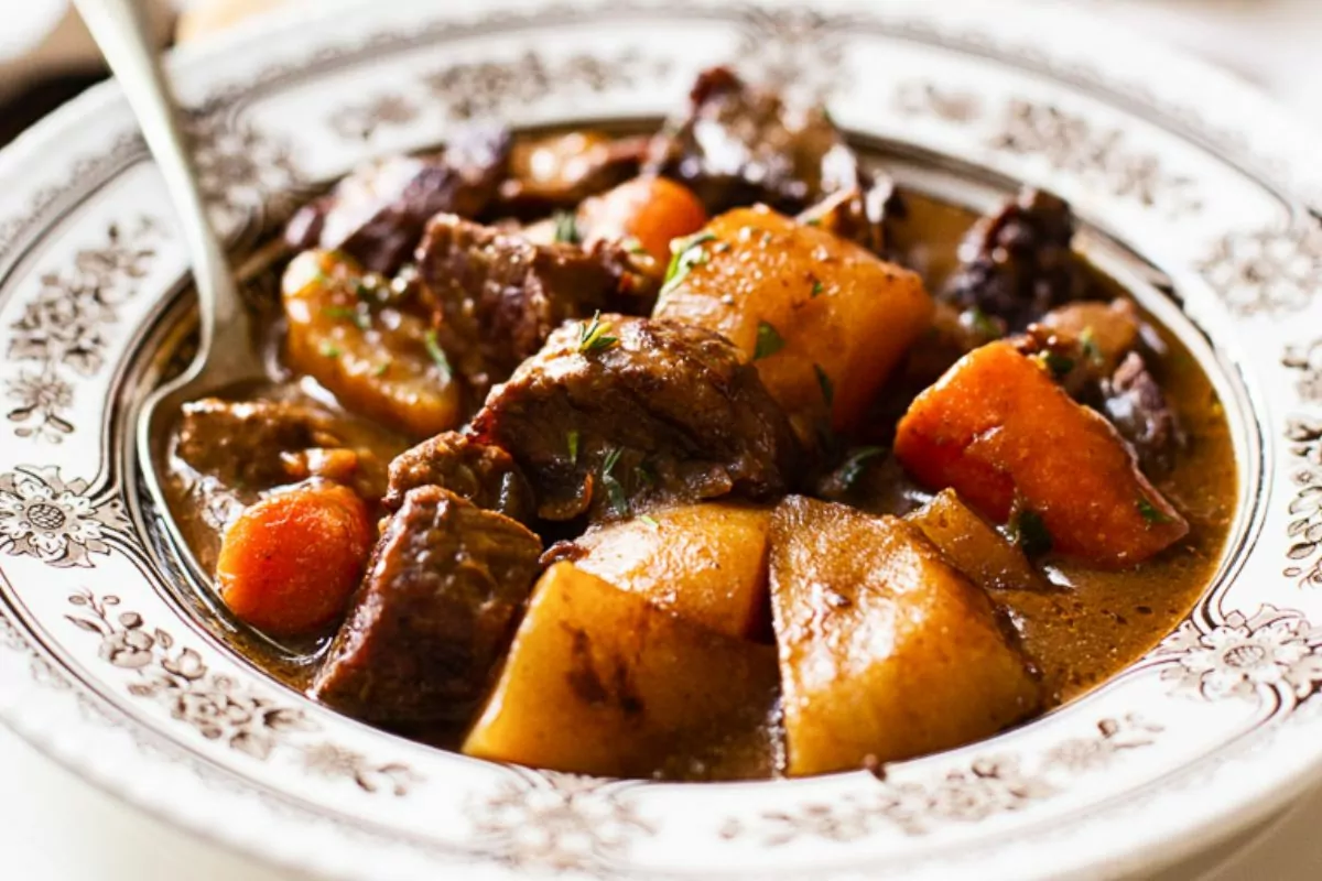 Irish beef stew with potatoes and carrots in bowl with spoon.