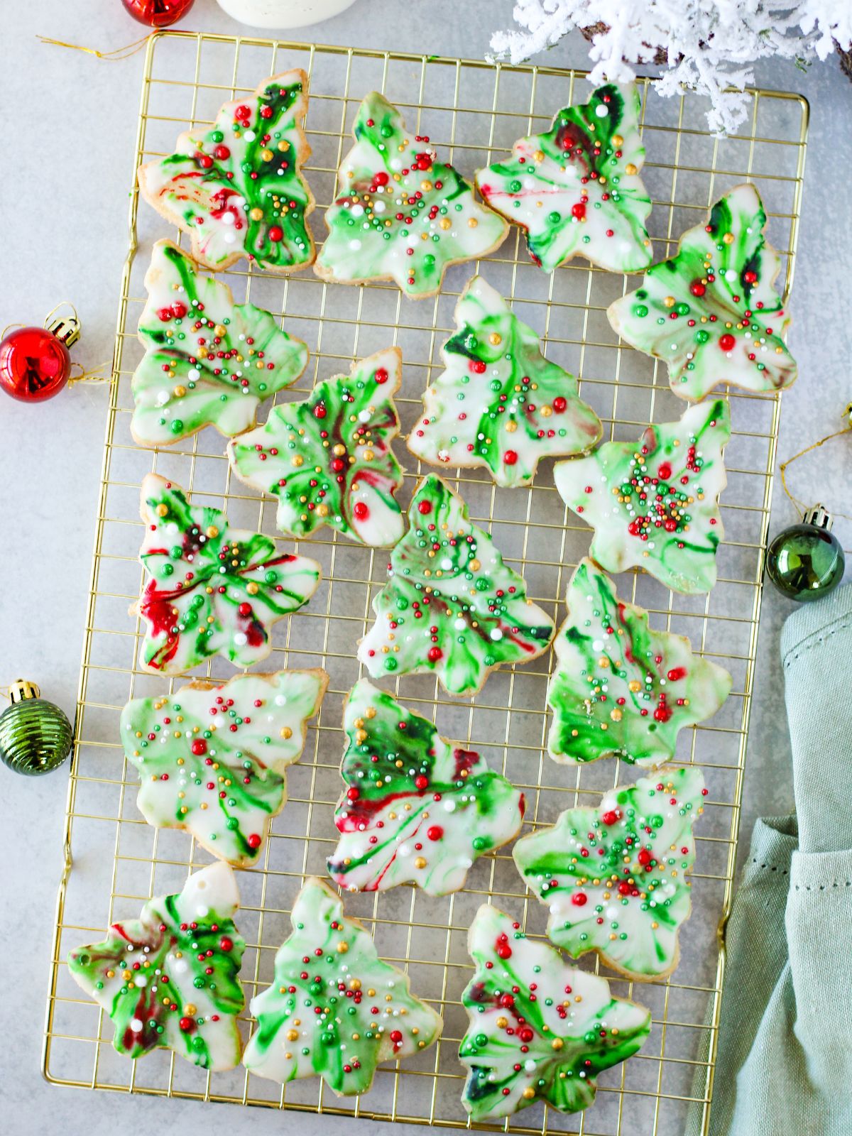 Christmas Tree Cookies with green marbled icing and sprinkles on a gold wire rack