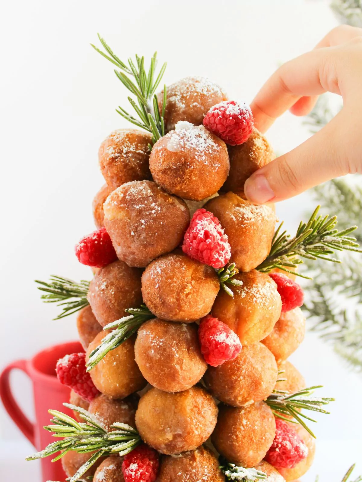 hand taking a donut hole from the donut Christmas tree