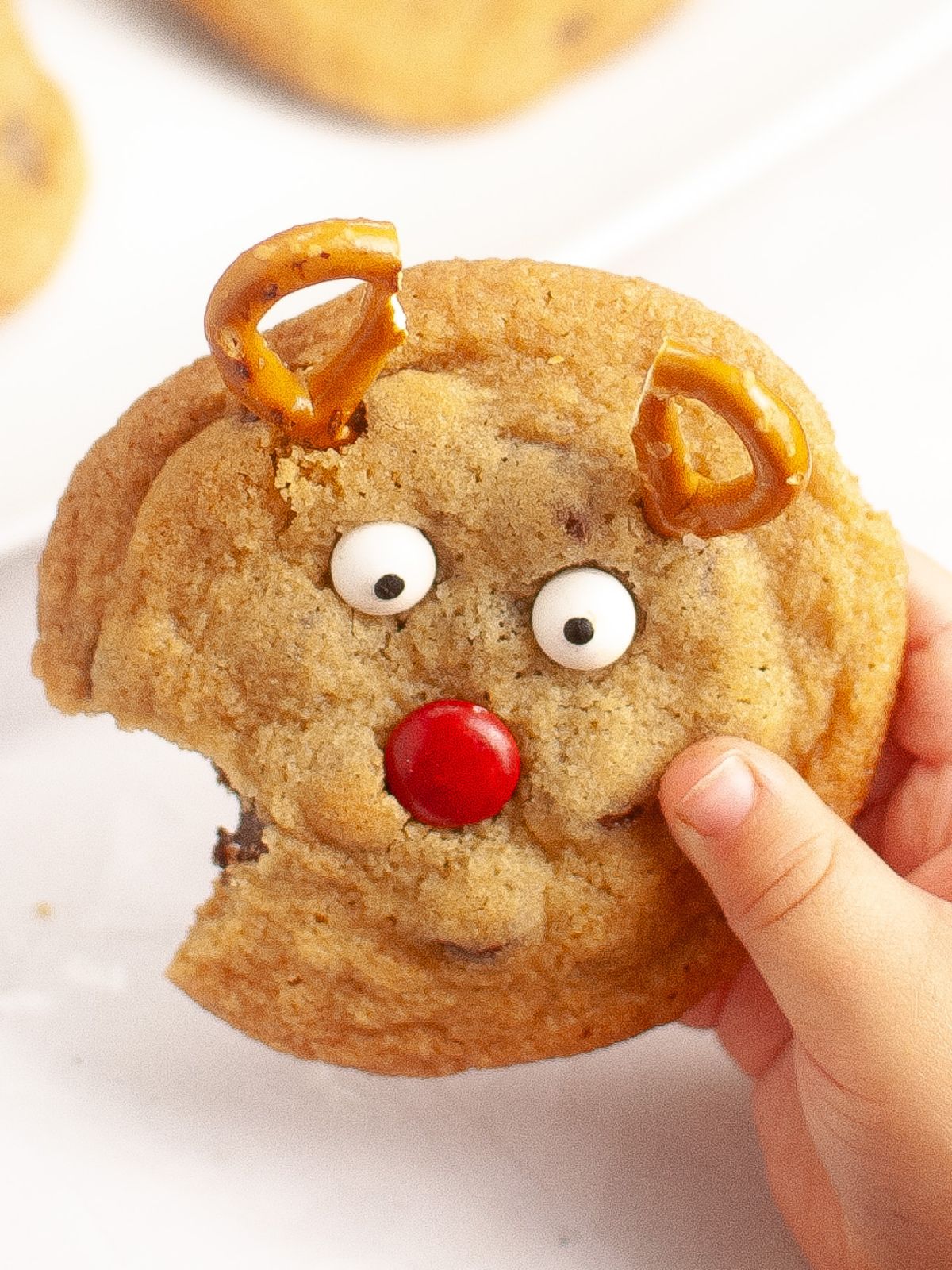 little hands holding reindeer cookie with bite.