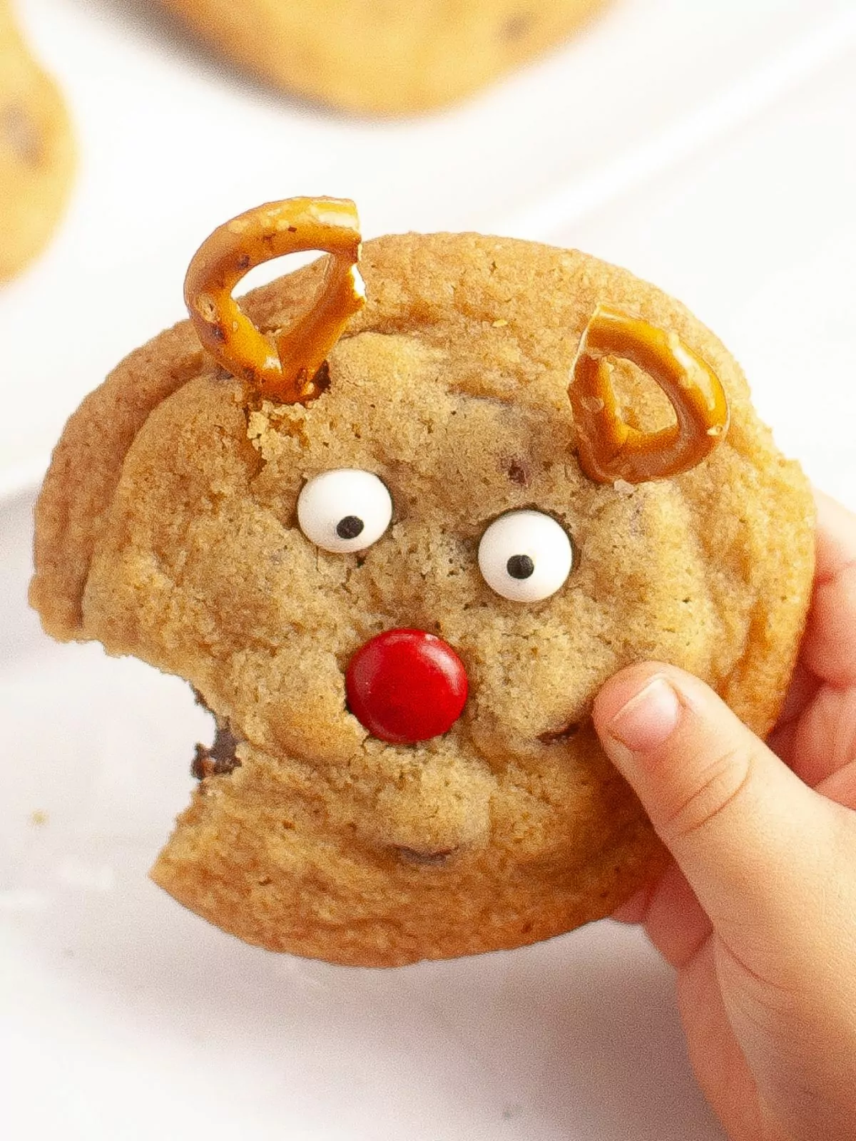 little hands holding reindeer cookie with bite.