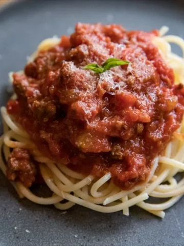 spaghetti with meat sauce on gray plate.