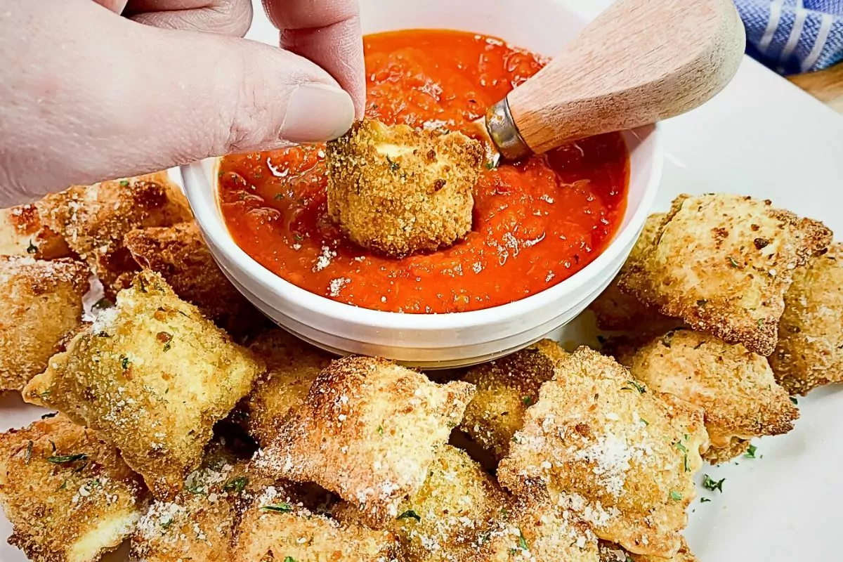 air fried ravioli on platter with bowl of marinara sauce.