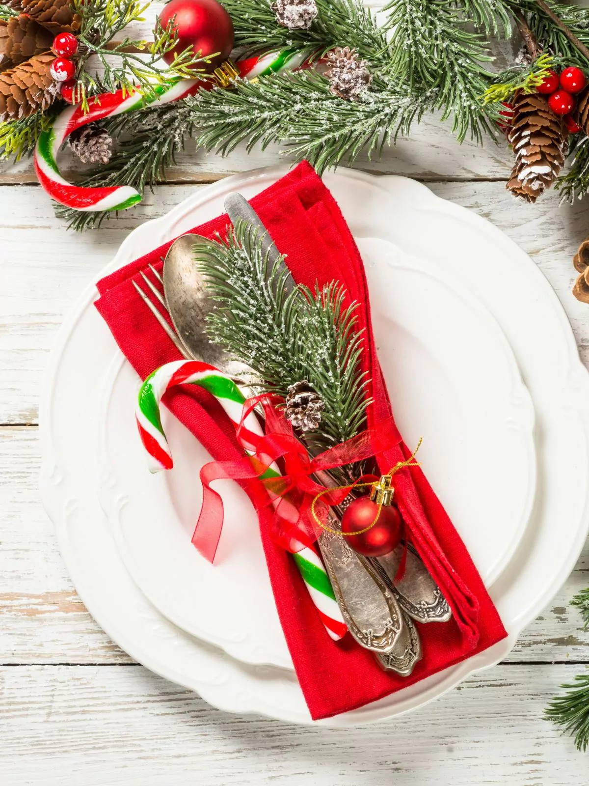 white plates with red napkin and decorations for Christmas.