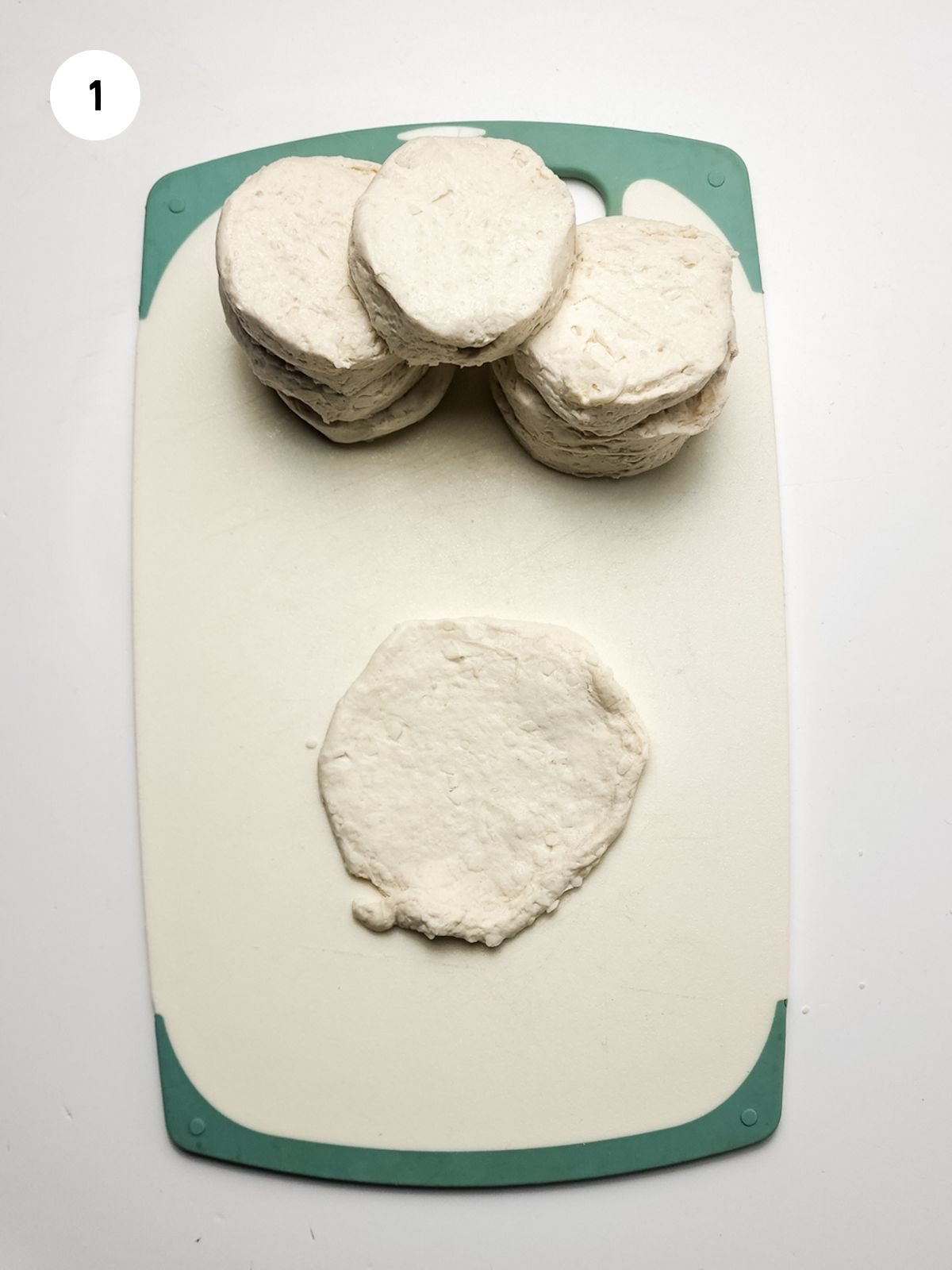 refrigerated biscuit flattened on a cutting board