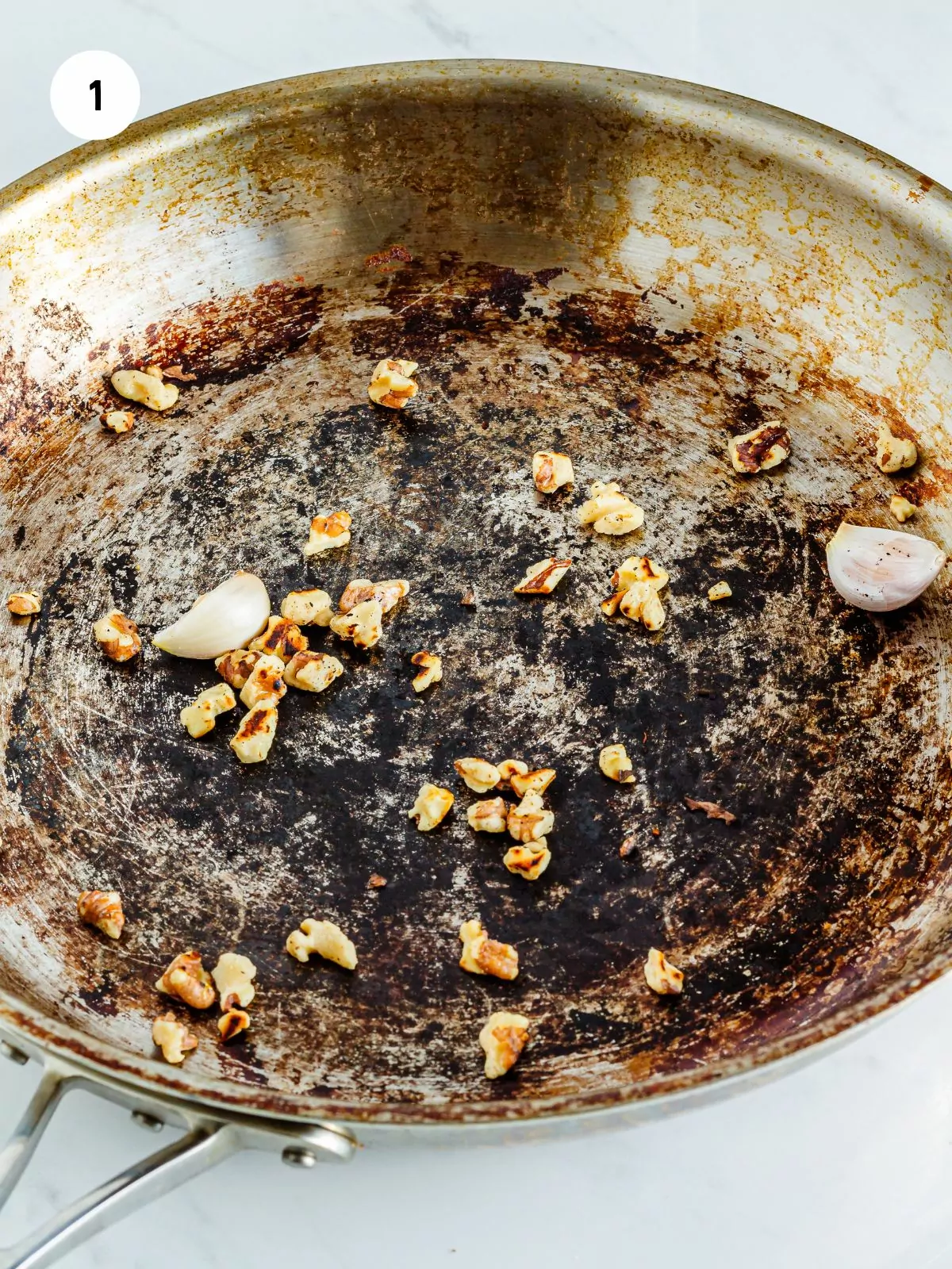 walnuts and garlic cloves toasting in a pan