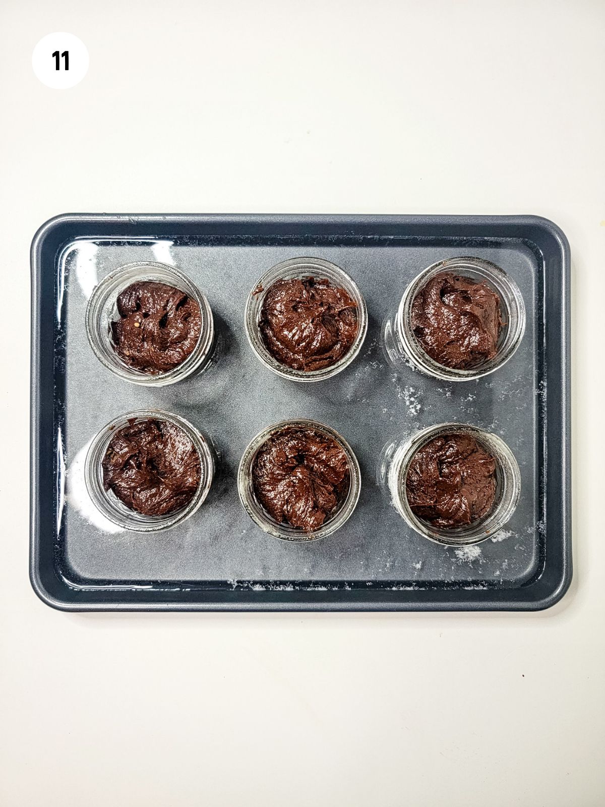 brownie batter in jars. The jars are in a pan with a water bath.