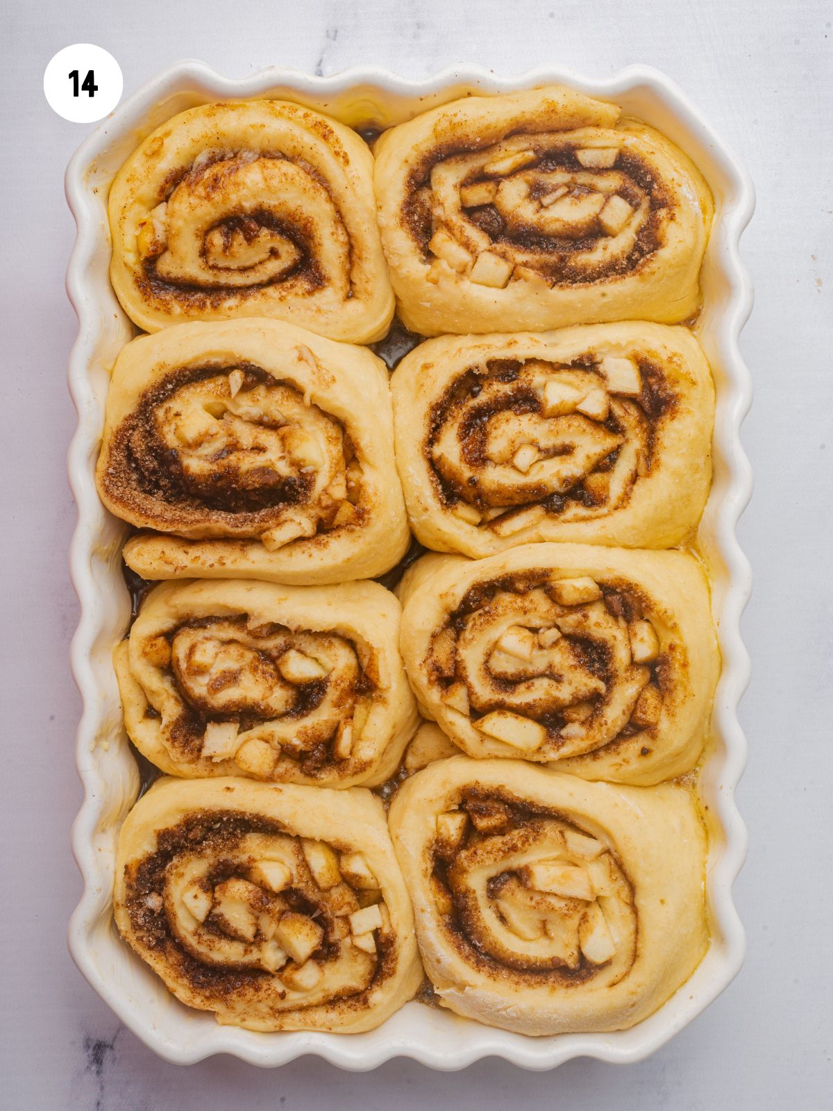 risen cinnamon rolls in a scalloped edge baking dish