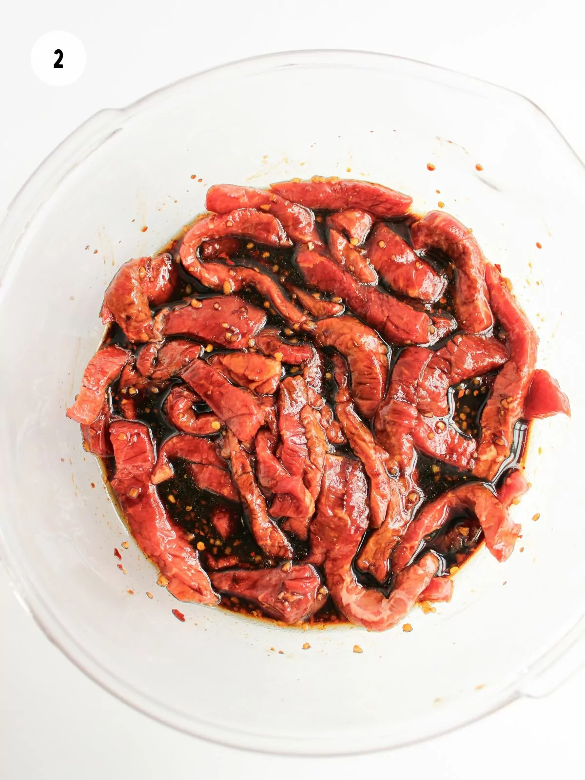 strips of steak in the bowl of marinade