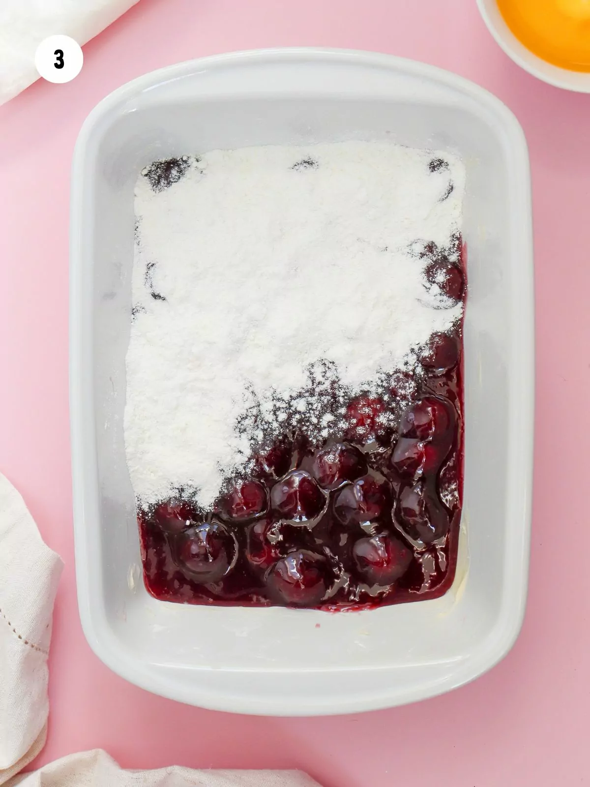 cake mix being added on top of the cherry pie filling