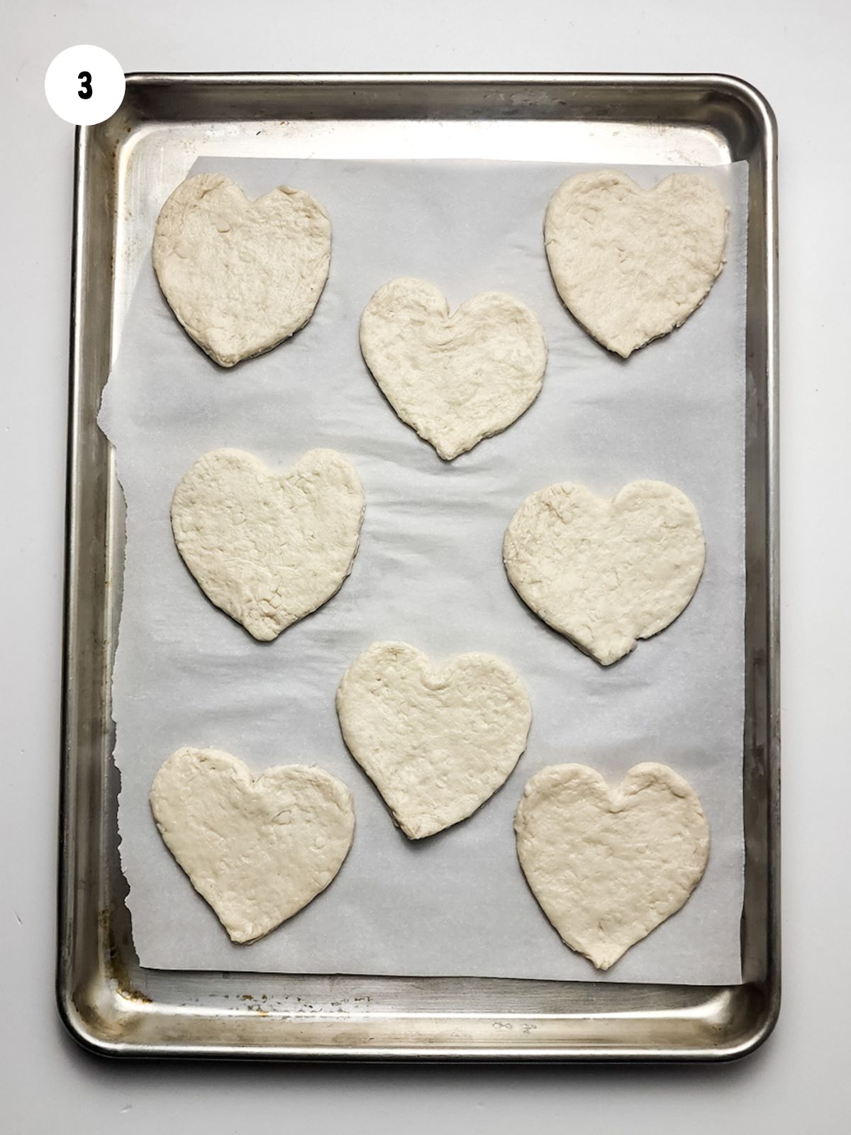 eight mini heart shaped dough on baking sheet