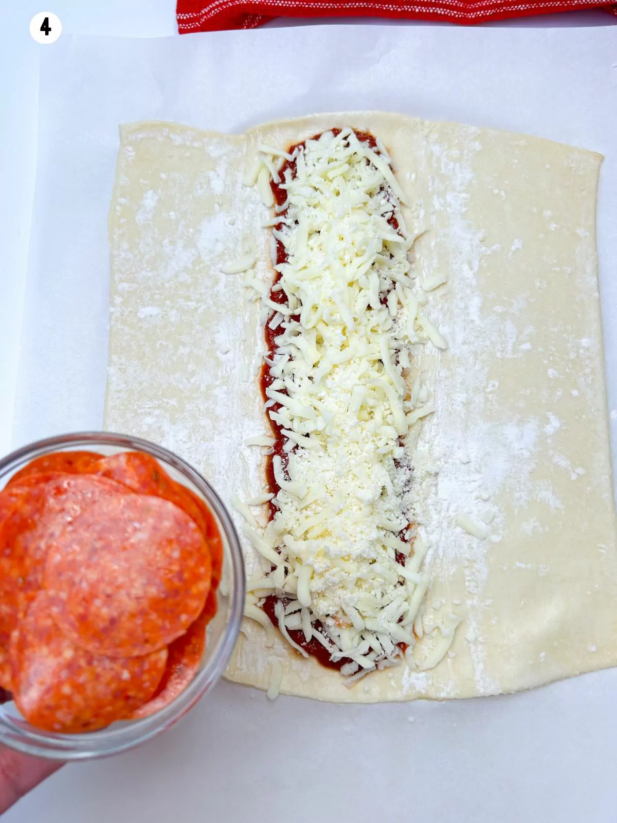 shredded mozzarella placed on top of the pizza sauce on the puff pastry and a bowl of pepperoni