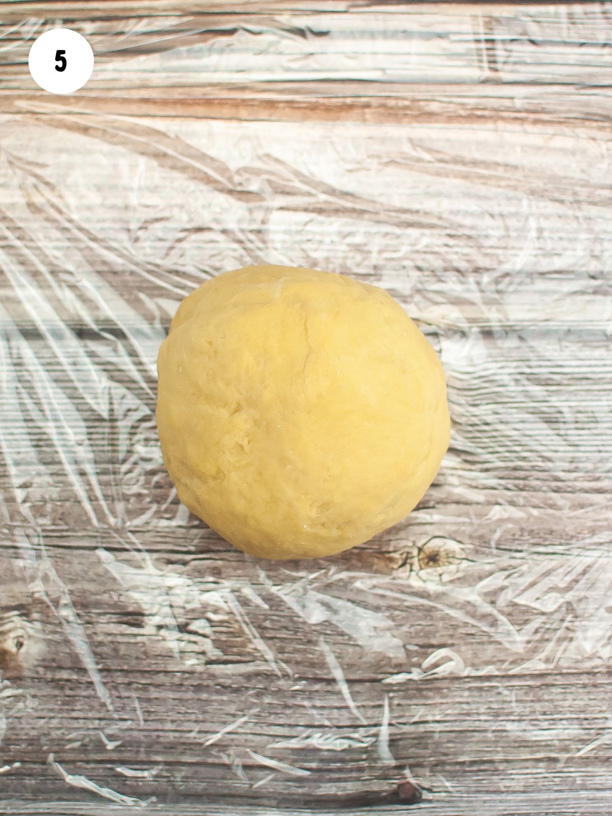 Smooth ball of dough on plastic wrap