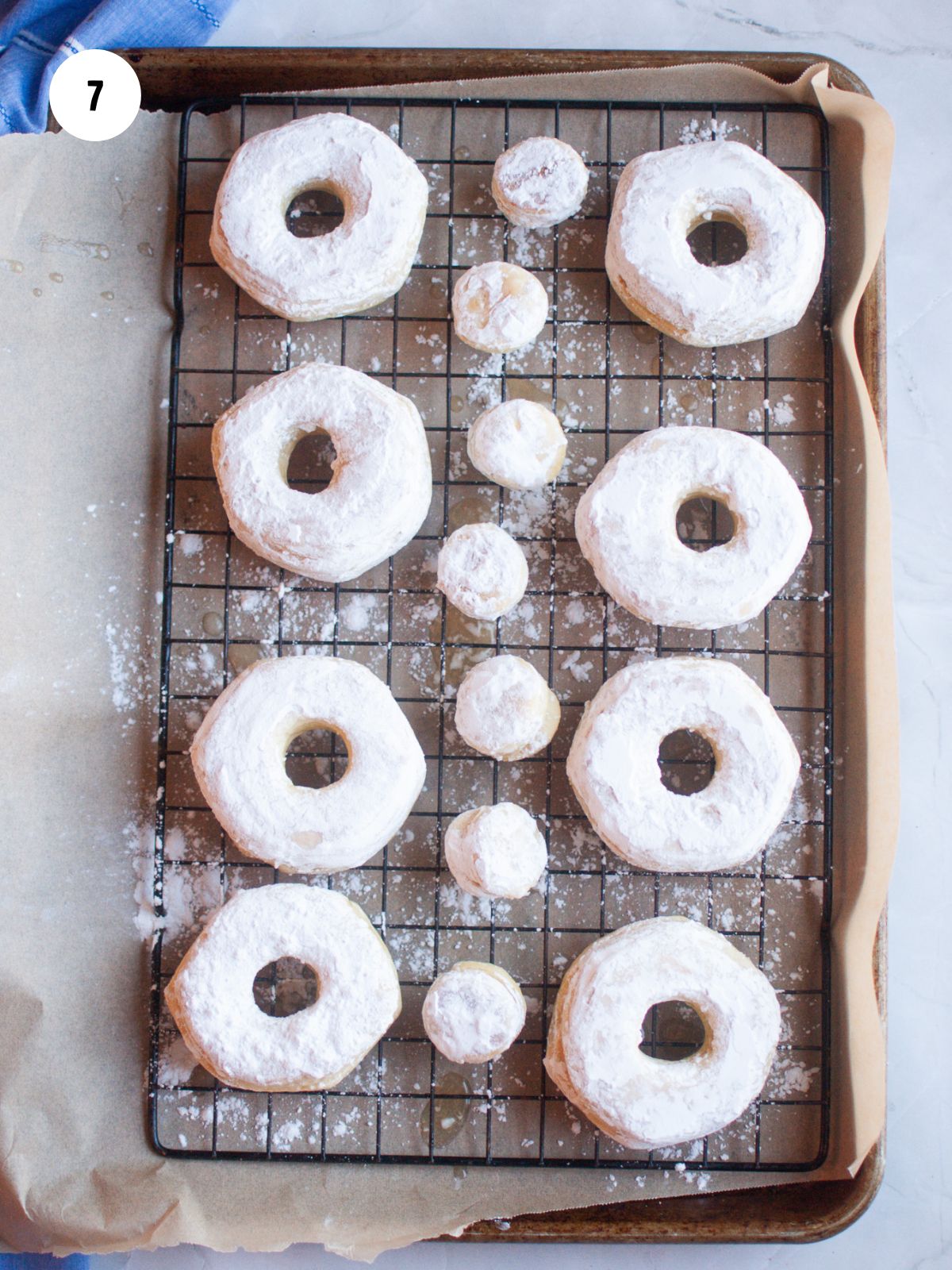 donuts and donut holes covered in powdered sugar on a wire rack