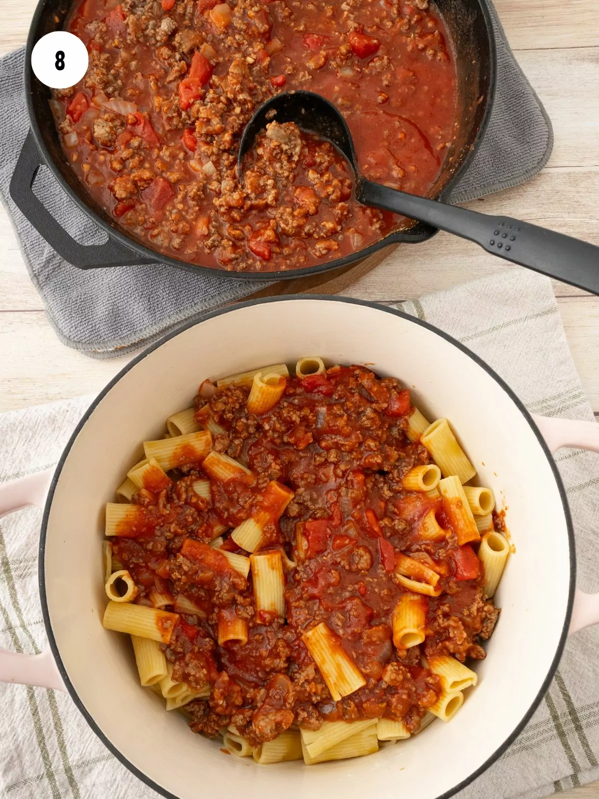 Pasta and sauce being combined in a bowl. At the top of the picture is the pan of sauce with a ladle.