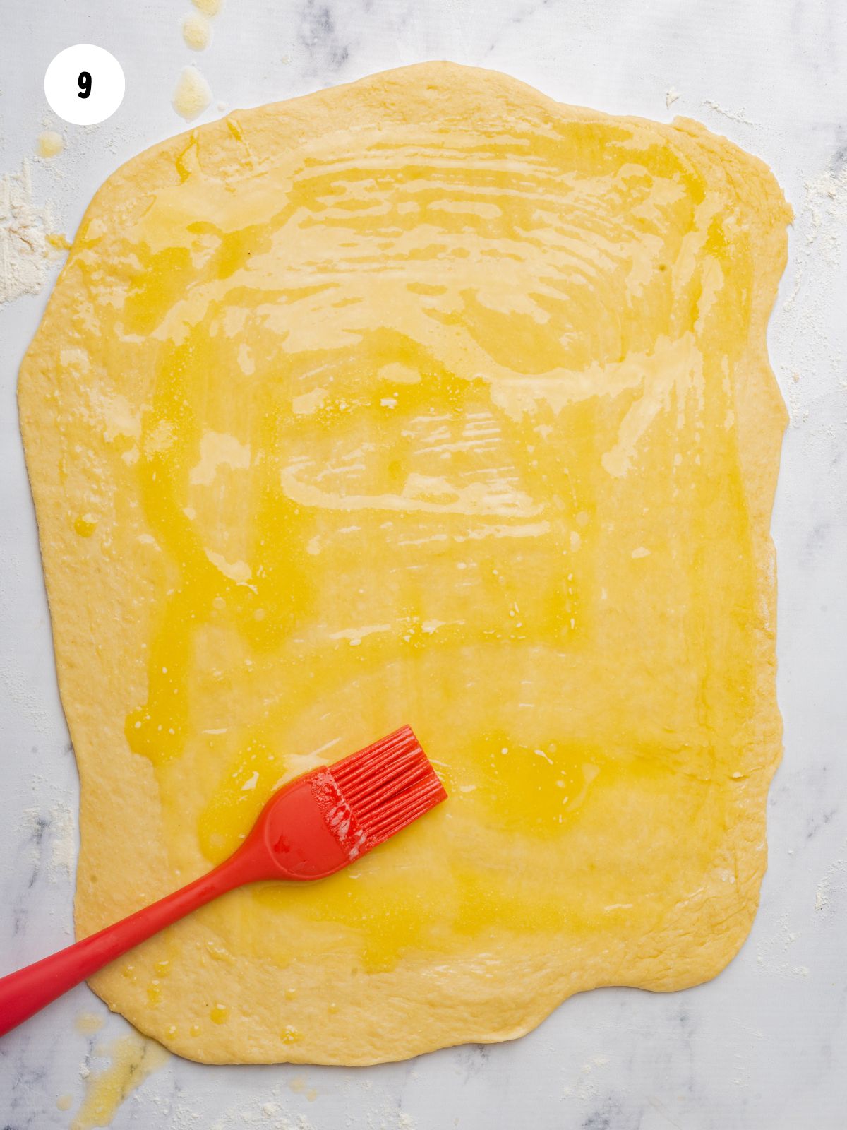 brushing butter on rolled out dough