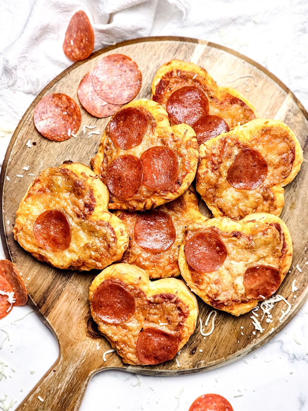 overhead view of heart shaped mini pizzas on a wood board