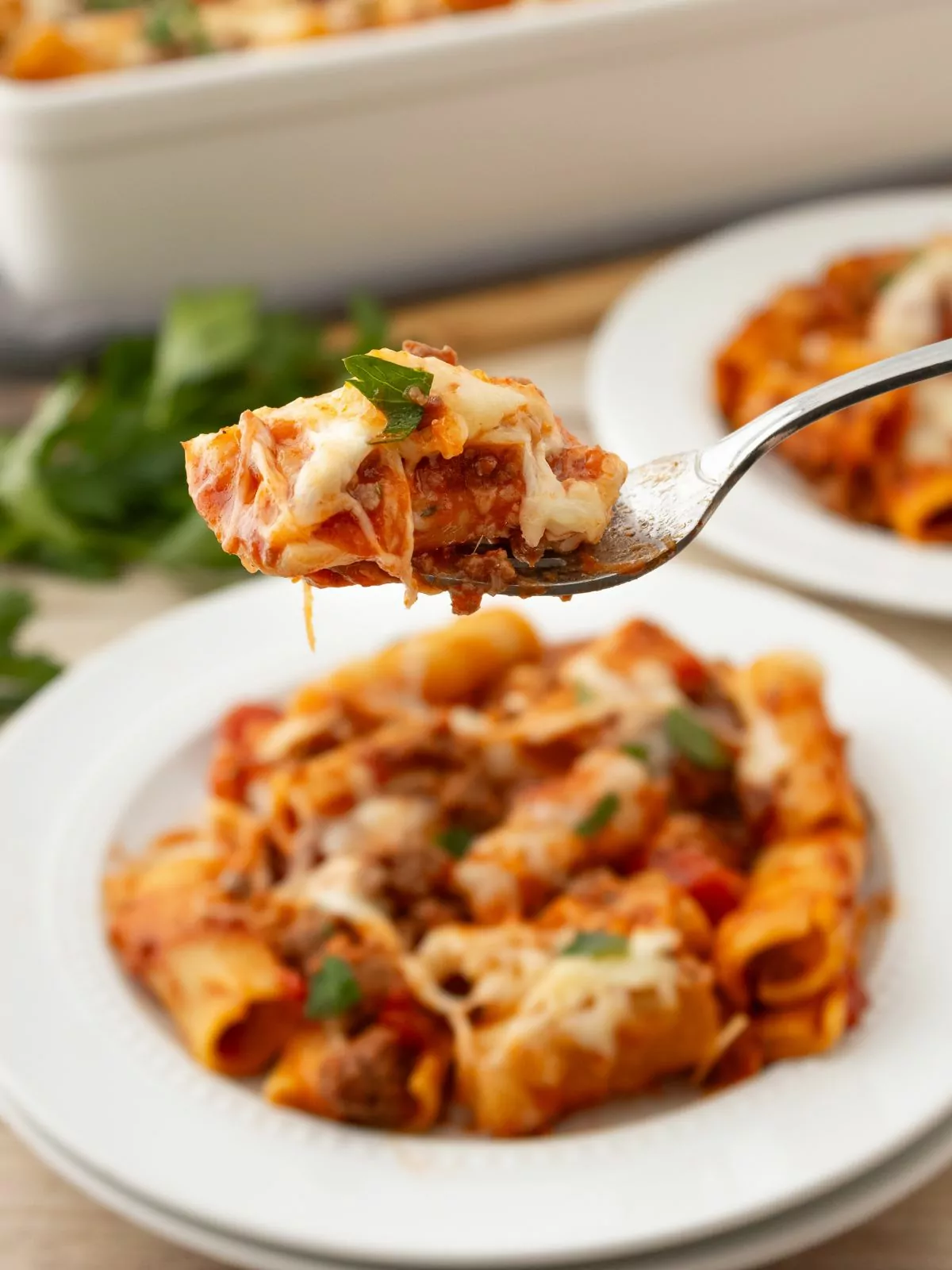 close up of a forkful of pasta with the serving on a plate in the background