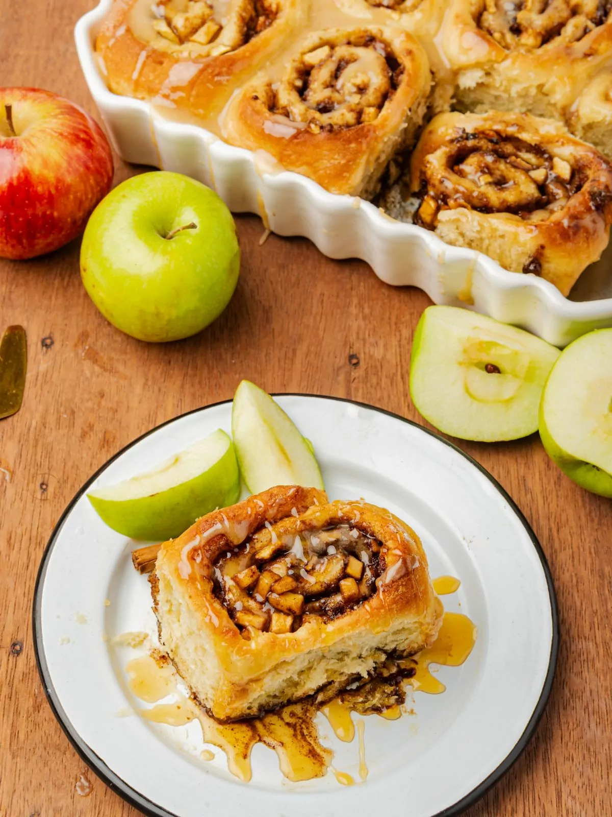 apple cinnamon roll served on a white plate with fresh apple slices.