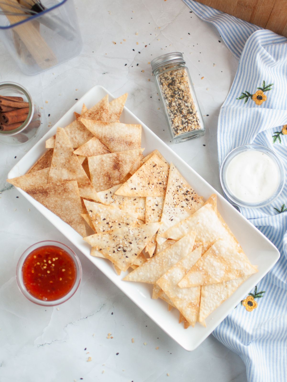 overhead view of Wonton Chips flavored with cinnamon sugar, everything seasoning, and sea salt. Dipping sauces in small cups next to the platter.