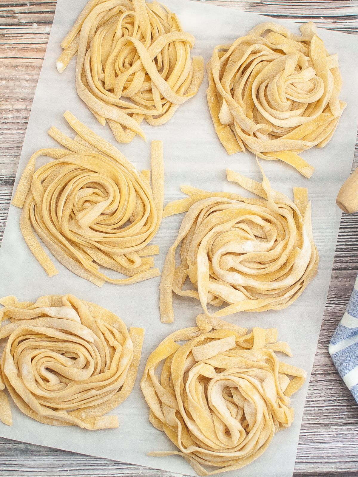 Six mounds of homemade fettuccine on a piece of parchment paper