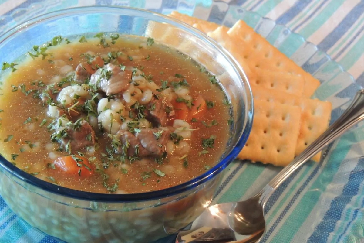 bowl of beef barley soup with crackers on the side.