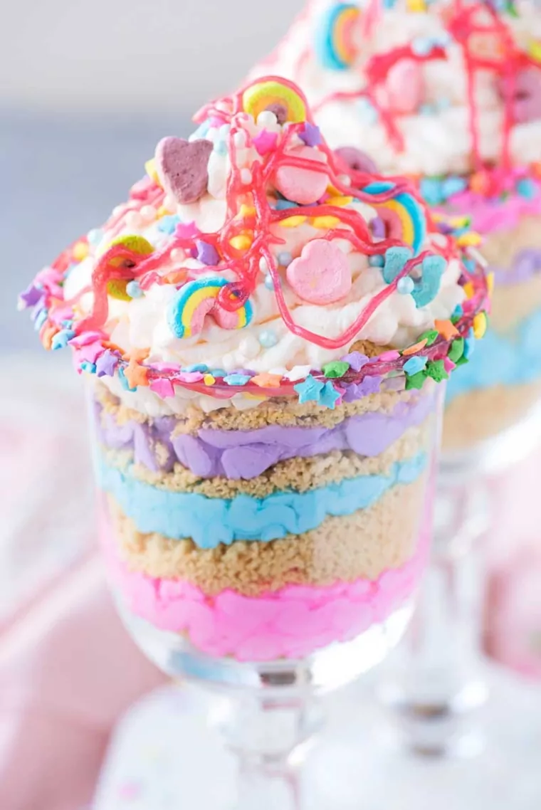 a glass of colored parfaits topped with sprinkles