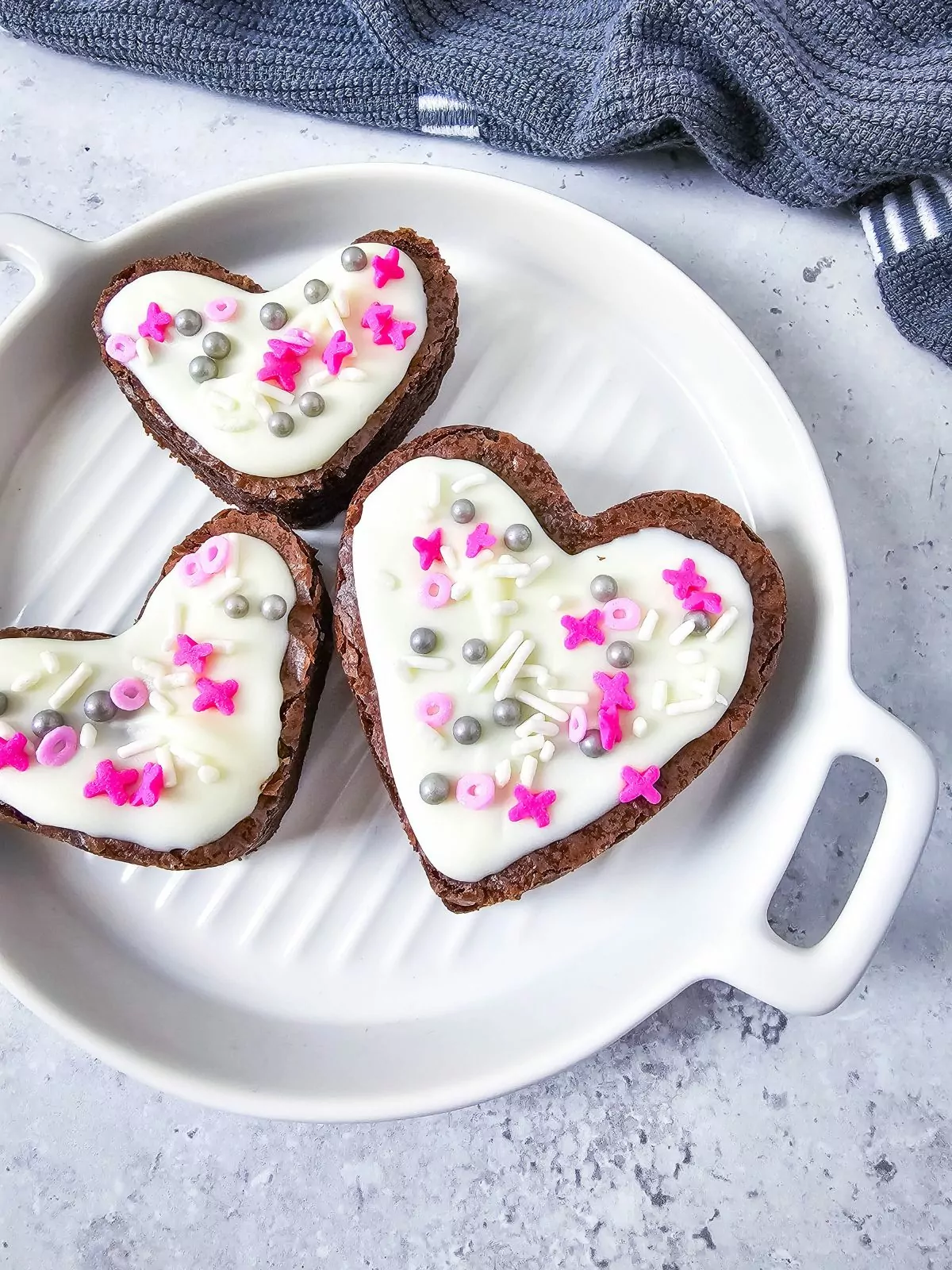 3 heart shaped brownies on white platter decorated for Valentine's Day.