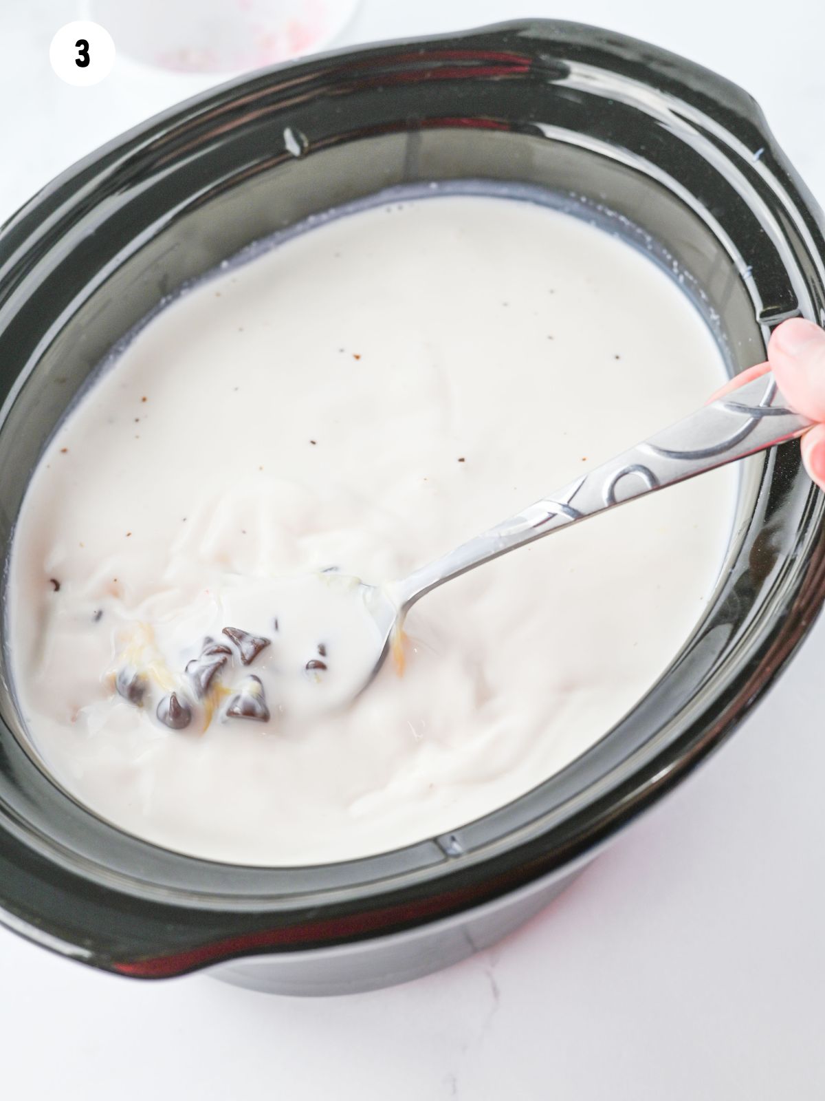 stirring melted chocolate chips with milk mixture in crock pot.