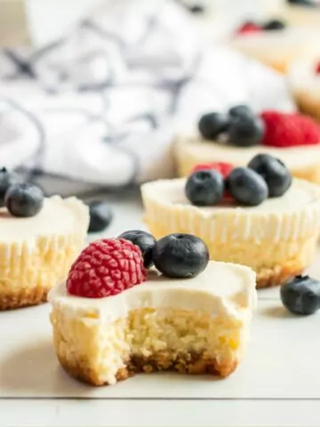 baked cheesecakes with fresh berries on cutting board.