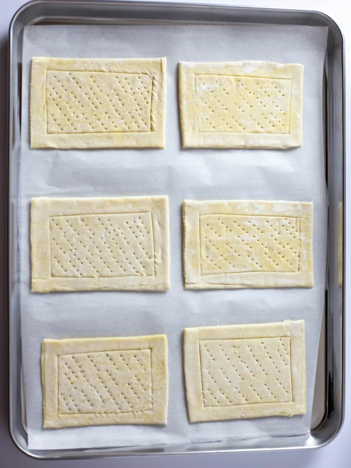 6 pastry squares fork pricked and scored for baking.