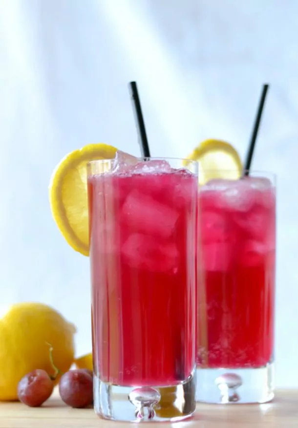 glass of Sparkling Grape Lemonade with ice and slice of lemon