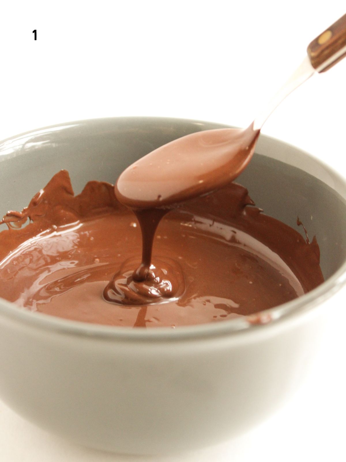 melted chocolate dripping off a spoon into a bowl