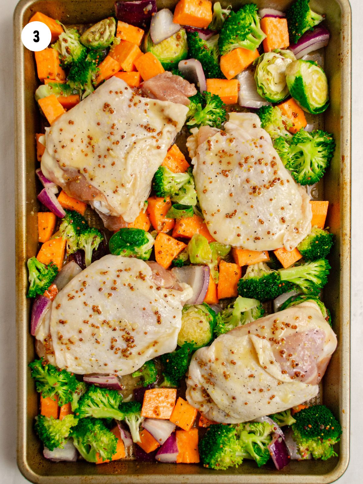 chicken thighs added to veggies on sheet pan