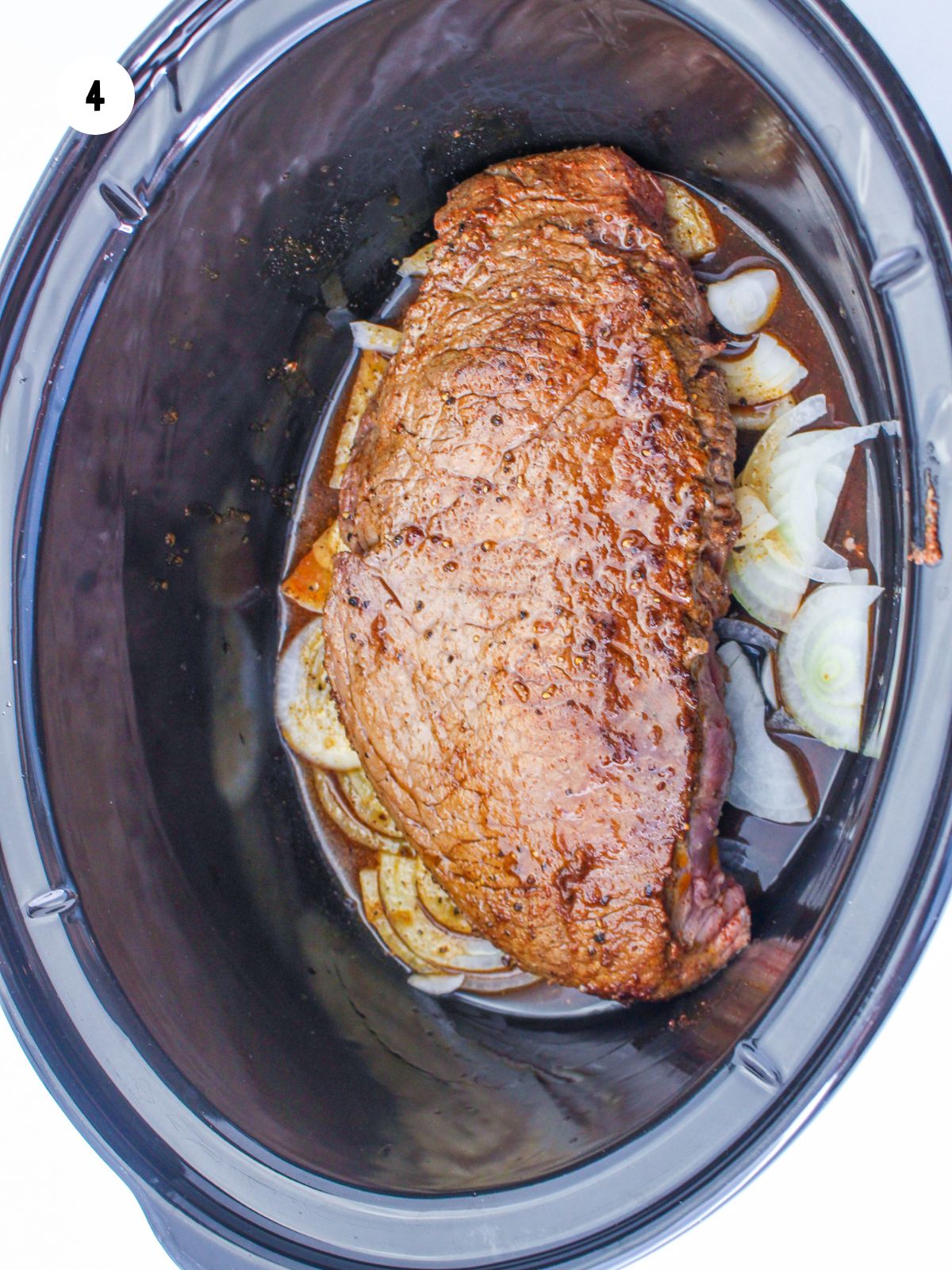 seared steak on onions in crock pot