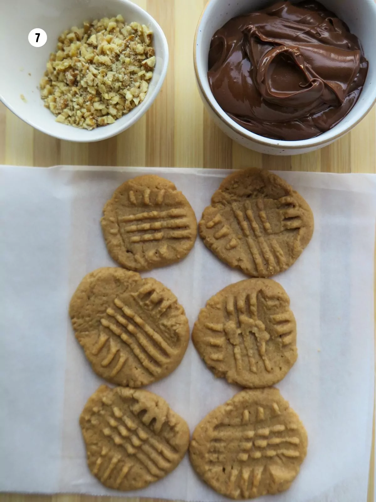 dip baked cookies in melted chocolate with crushed nuts