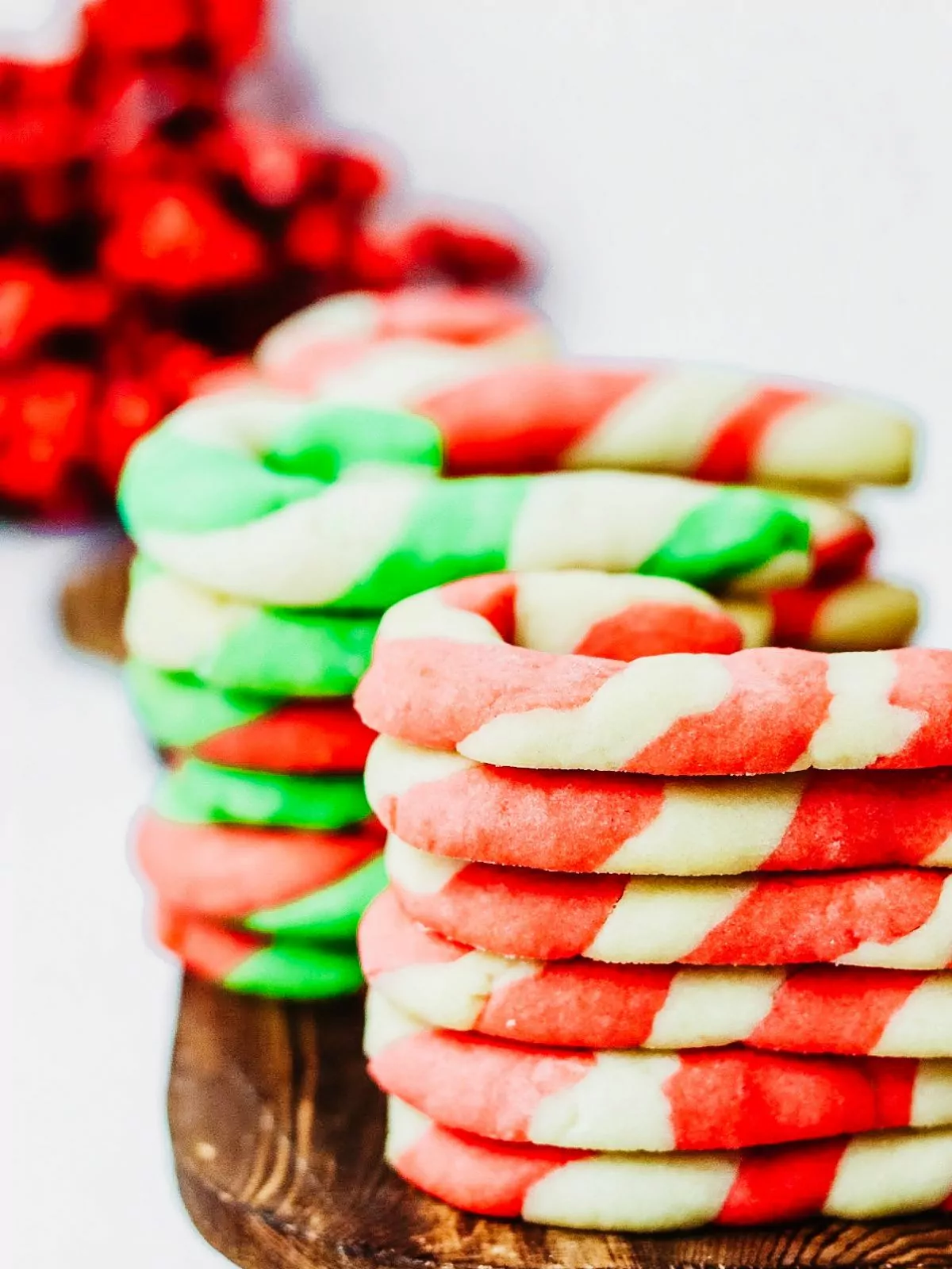 candy cane striped sugar cookies stacked on cutting board.