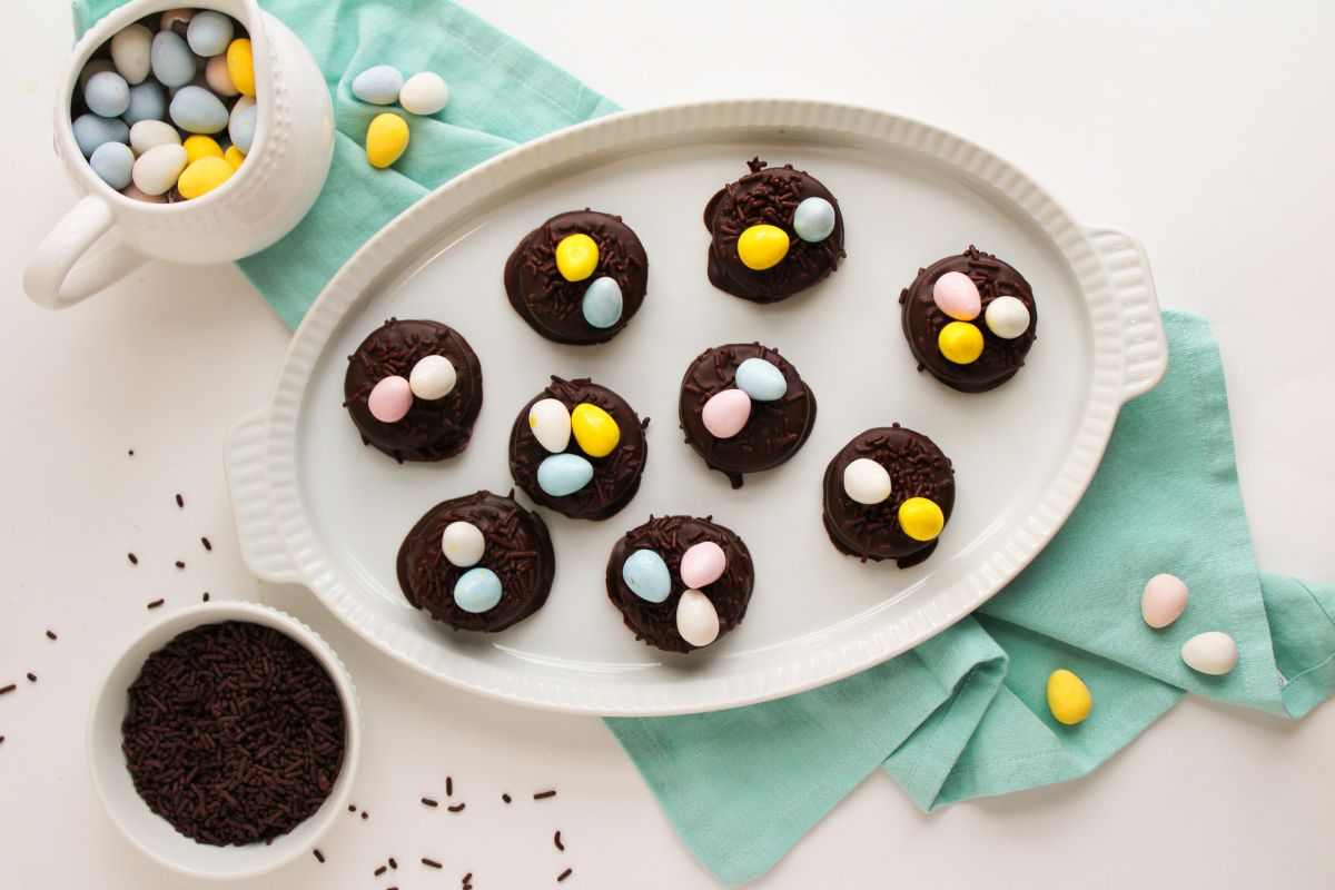 oval platter filled with chocolate covered oreos topped with chocolate sprinkles and pastel mini chocolate eggs